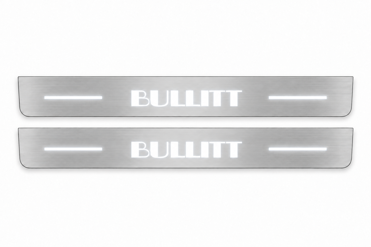 Product visualization: two flat original bullitt-s550-bars Stainless front plates with exact artwork and white lower/end LEDs flat brushed stainless steel door sill plates with white LED artwork and edges, white background.