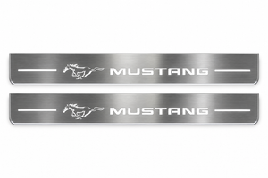 Product visualization: two exact mustang-pony-legacy flat Stainless front sill plates with original artwork, neutral white LEDs and own thin-edge geometry flat brushed stainless steel door sill plates with white LED artwork and edges, white background.