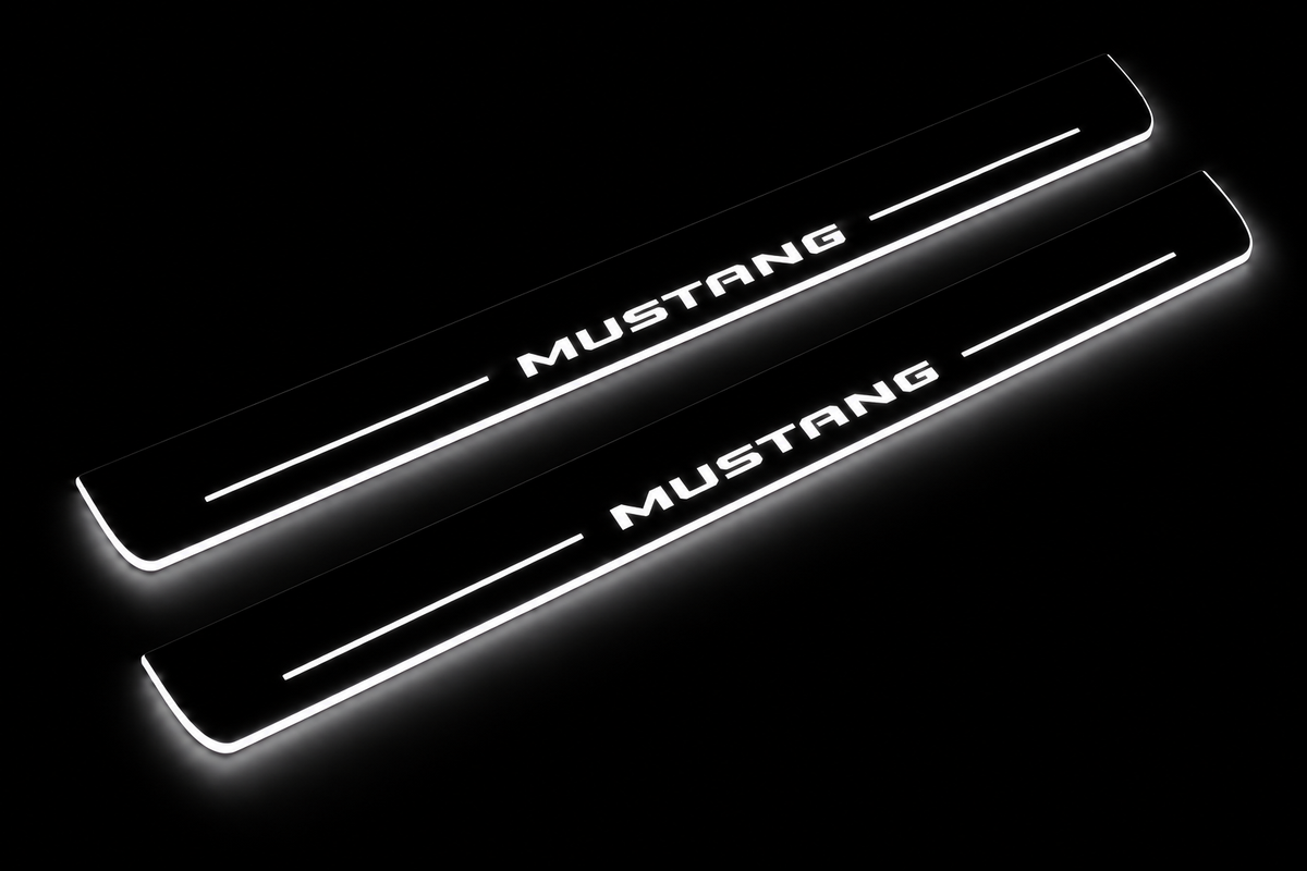 Product visualization: MUSTANG compact block lettering, two flat source front plates flat brushed stainless steel door sill plates with white LED artwork and edges, dark background.