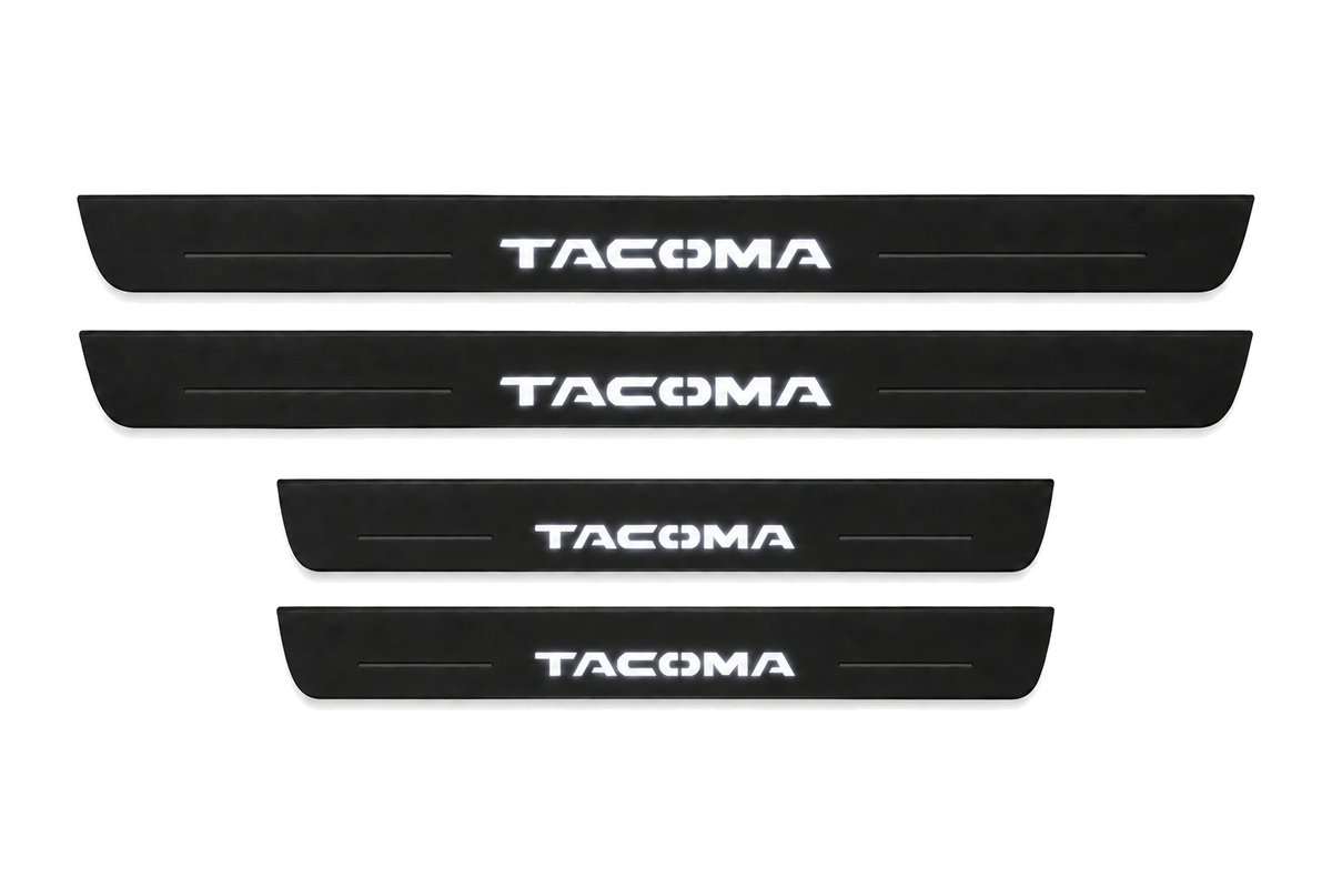 Catalogue illustration of two long black Matte PRO front sill plates and two shorter rear plates with TACOMA lettering illuminated on top. Side edges unlit; vehicle-specific dimensions are not depicted. FRONT option includes front plates only.
