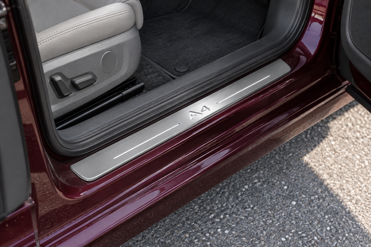 Daylight product visualization of a brushed stainless sill with A4 artwork and two narrow light bars in a burgundy Audi doorway.
