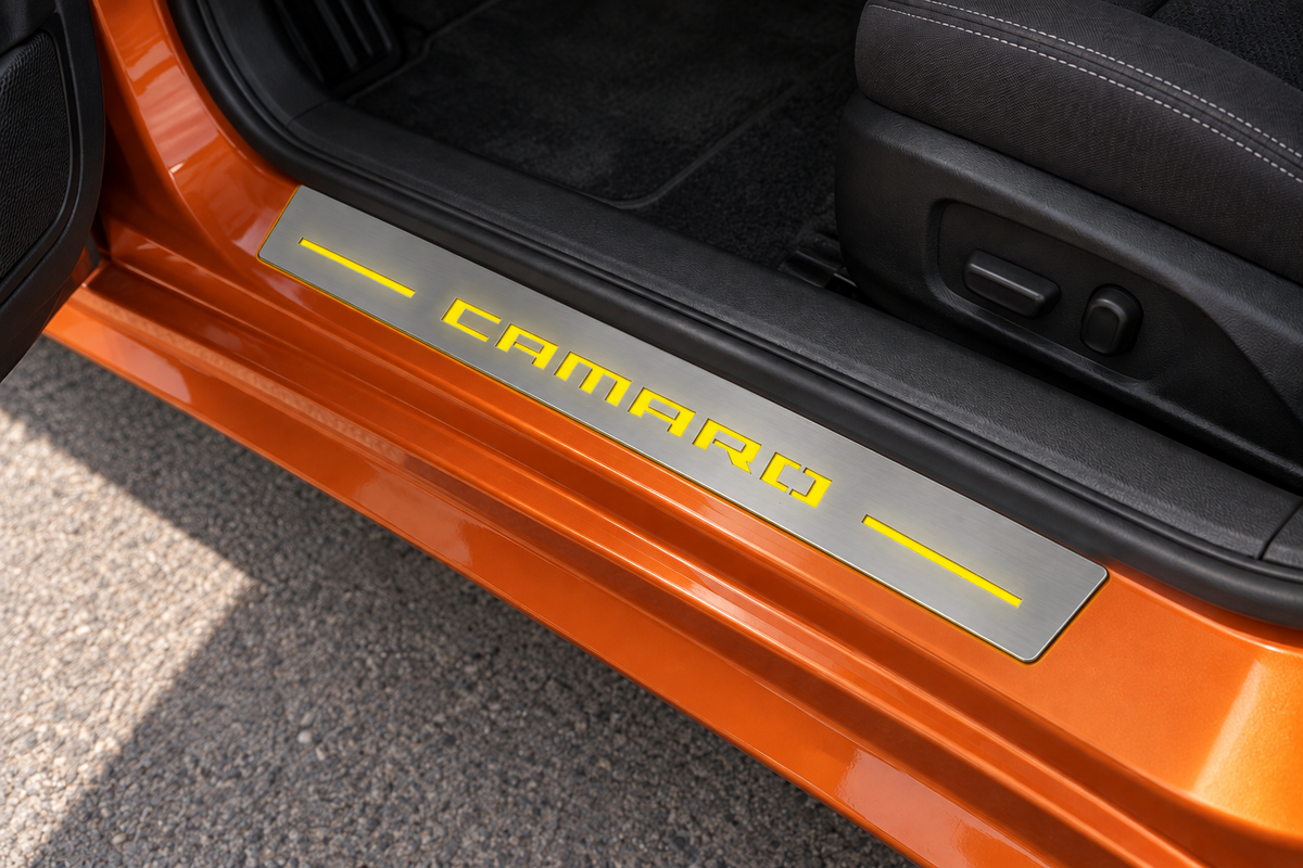 CAMARO Stainless sill with yellow lettering and light bars on orange metal directly against rubber seal — product visualization