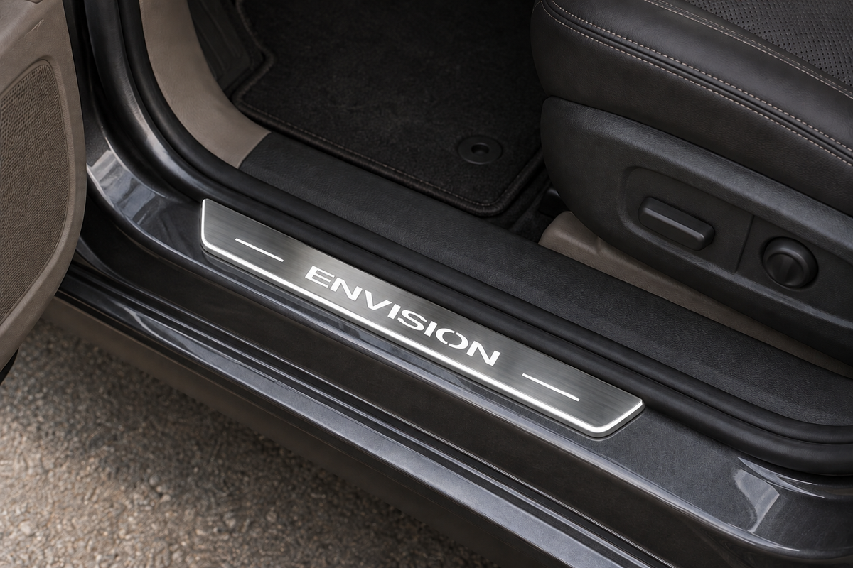 Buick Envision Stainless sill visualization directly against the rubber seal on exposed grey metal, white ENVISION lettering and illuminated lower contour.
