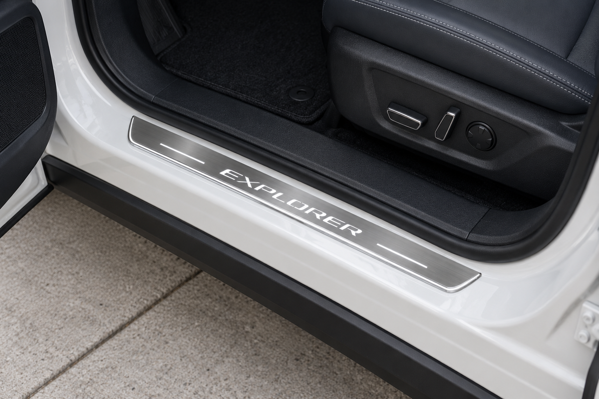 Product visualization of a grey stainless Explorer-lettering sill with white light bars and edge on a white SUV threshold beside a dark seat.