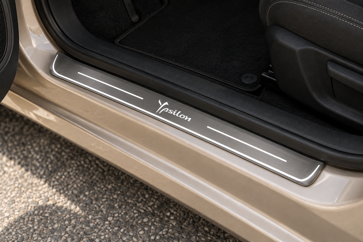 Lancia Ypsilon Stainless Steel sill visualization with cursive Ypsilon lettering, white side bars and edge on grey brushed steel in a champagne hatchback doorway.