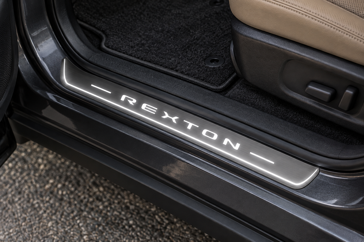 SsangYong Rexton Y400 Stainless Steel sill visualization with white REXTON lettering, side lines and edge on grey brushed steel in a dark SUV doorway.