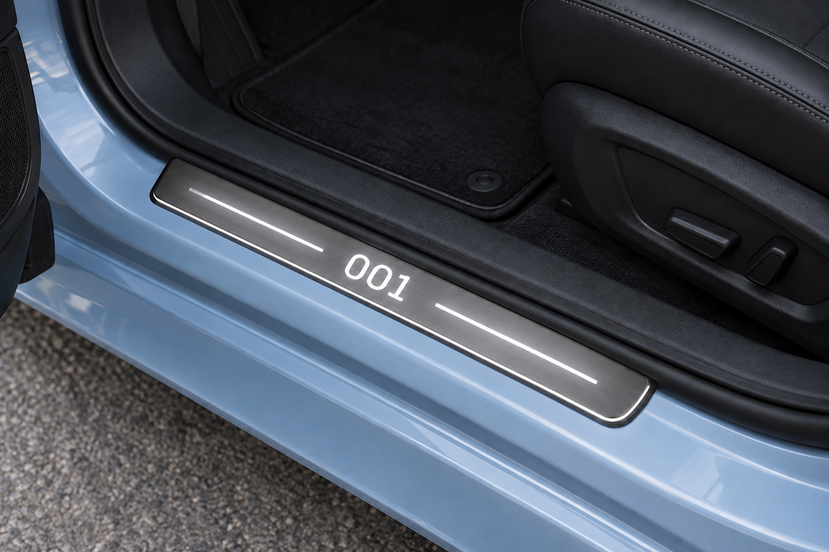 Zeekr 001 Stainless sill visualization directly against the rubber seal on exposed blue-silver metal, white 001 lettering, two top bars and thin Stainless edge lighting.