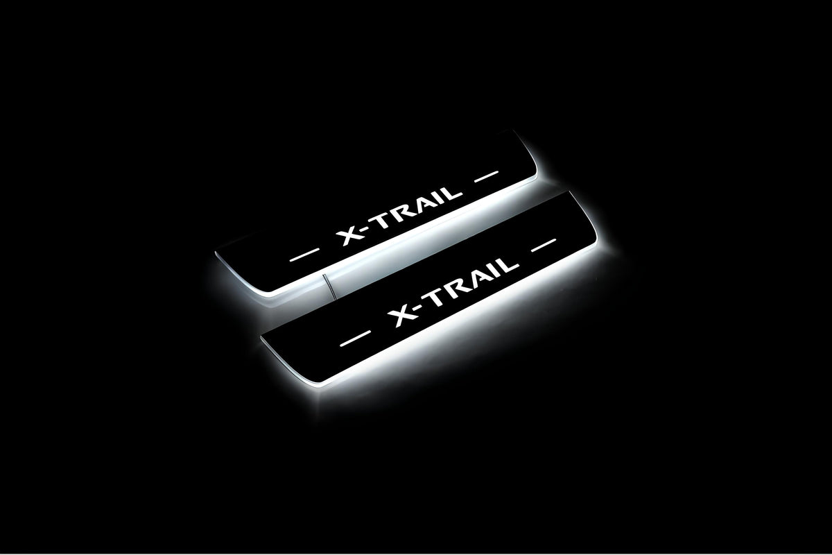 Two short door sill plates with X-Trail lettering and edges illuminated in white, angled view on a dark background.