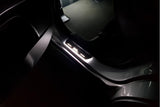 Short door sill with illuminated XL lettering fitted beside a vehicle rear seat; installation example.