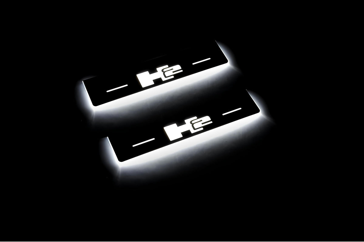 Two short door sill plates with H2 lettering and edges illuminated in white, angled view on a dark background.