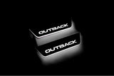 Two short door sill plates with Outback lettering and edges illuminated in white, angled view on a dark background.