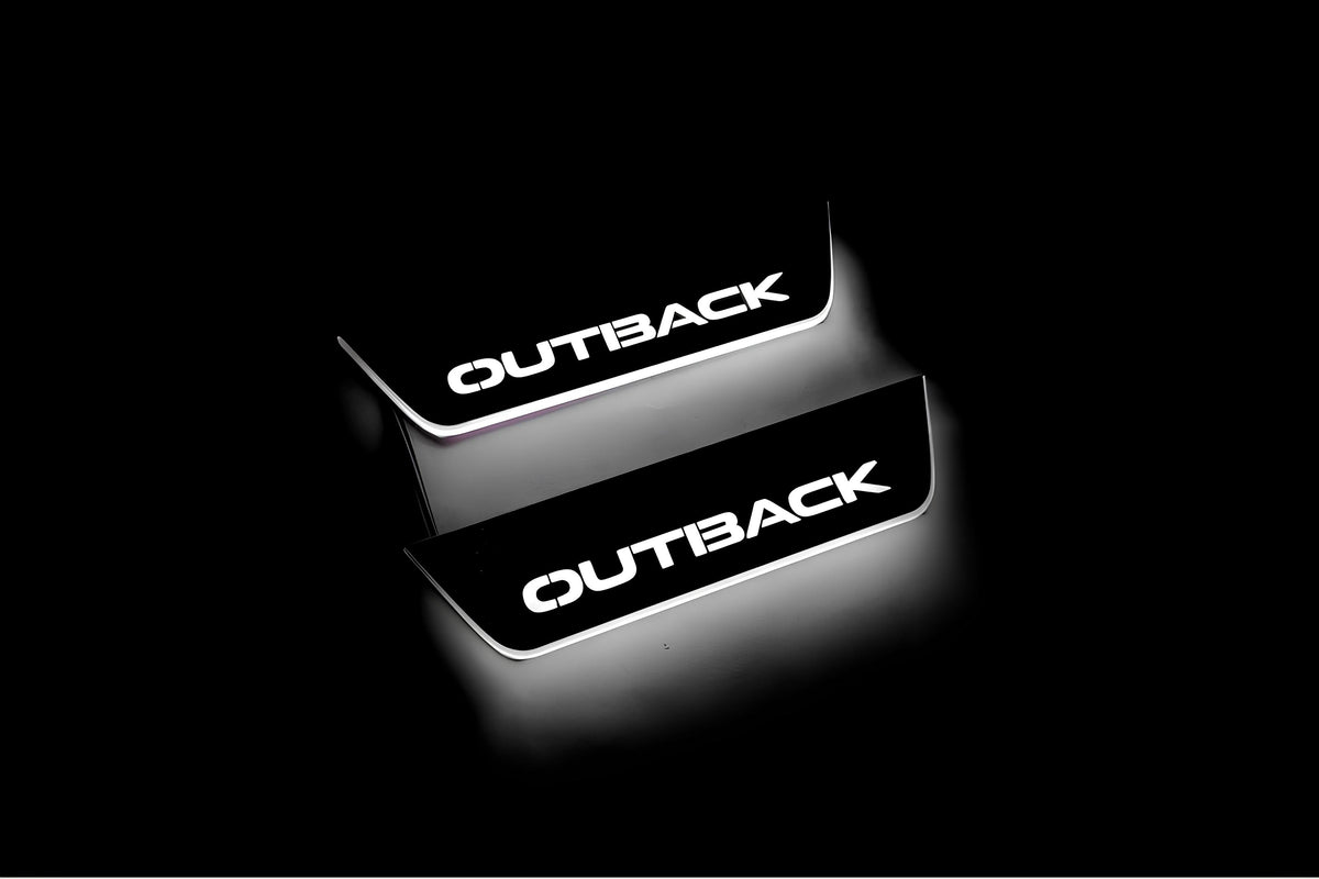 Two short door sill plates with Outback lettering and edges illuminated in white, angled view on a dark background.