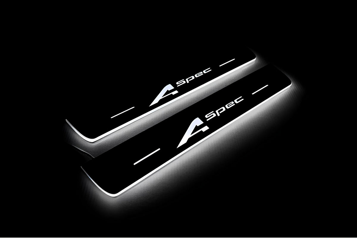 Two short door sill plates with A-Spec lettering and edges illuminated in white, angled view on a dark background.