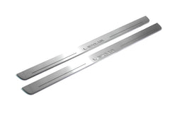 Two long silver-finished door sill plates with Lexus lettering on a light background, angled view.