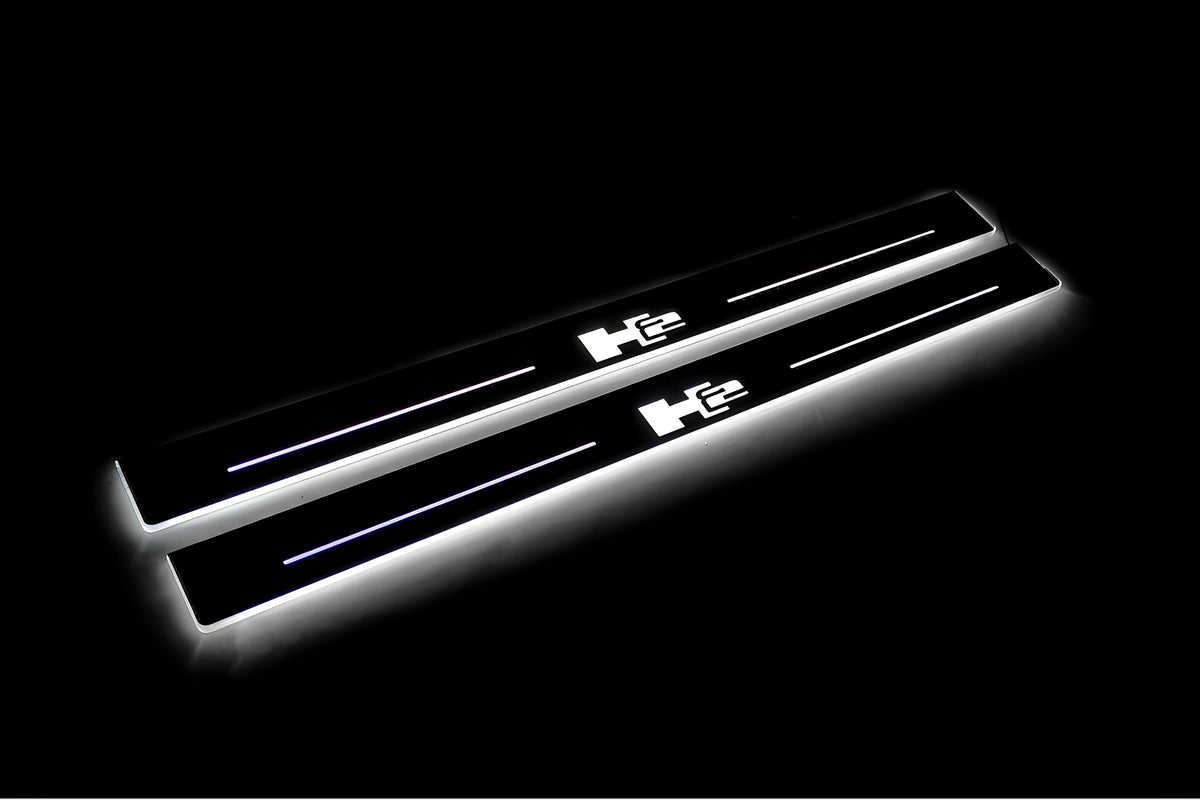 Two long door sill plates with H2 lettering and edges illuminated in white, angled view on a dark background.