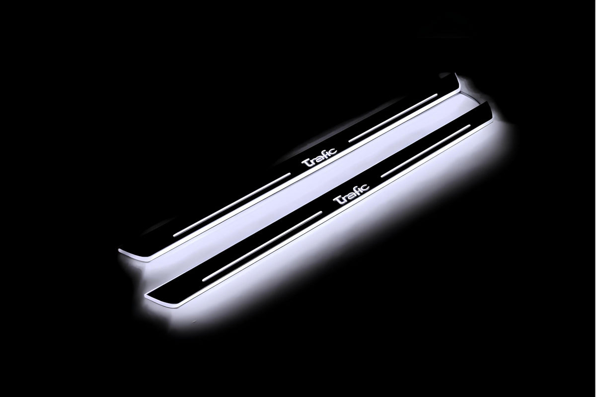 Two long door sill plates with Trafic lettering and edges illuminated in white, angled view on a dark background.