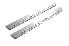 Two long silver-finished door sill plates with C-Crosser lettering on a light background, angled view.