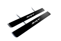 Two black door sill plates with white SRT lettering and visible wiring on a light background.