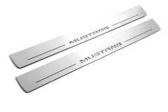 Two long silver-finished door sill plates with Mustang lettering on a light background, angled view.