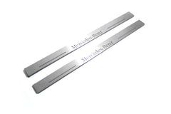 Two long silver-finished door sill plates with Mercedes-Benz lettering on a light background, angled view.