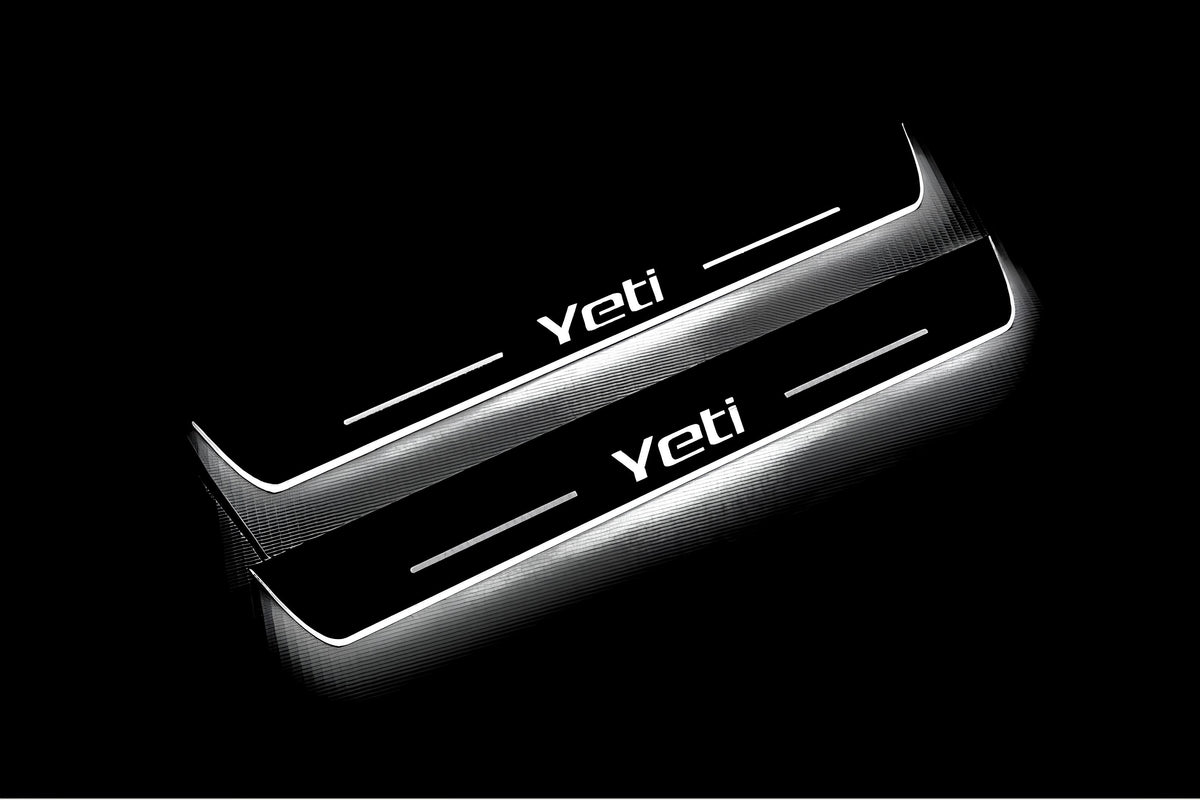 Two long door sill plates with Yeti lettering and edges illuminated in white, angled view on a dark background.