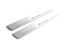 Two long silver-finished door sill plates with Tucson lettering on a light background, angled view.