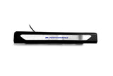 Black molded threshold trim with a silver insert bearing blue M Performance lettering, straight-on view.