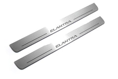 Two long silver-finished door sill plates with Elantra lettering on a light background, angled view.