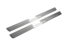 Two long silver-finished door sill plates with TRD Pro lettering on a light background, angled view.