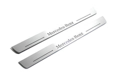 Two long silver-finished door sill plates with Mercedes-Benz lettering on a light background, angled view.