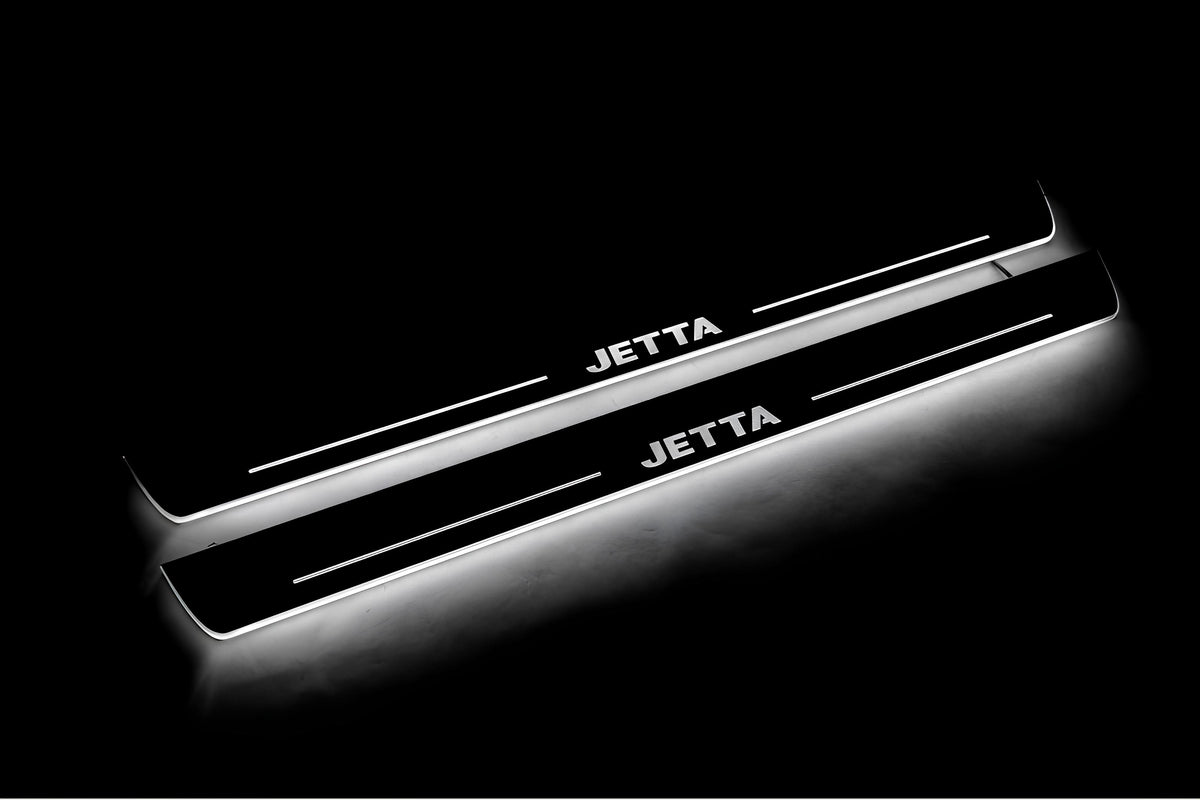 Two long door sill plates with Jetta lettering and edges illuminated in white, angled view on a dark background.