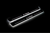 Two long door sill plates with X-Trail lettering and edges illuminated in white, angled view on a dark background.