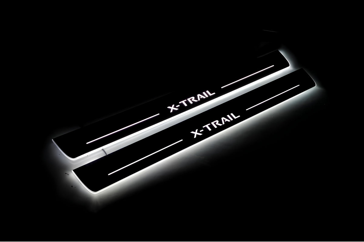 Two long door sill plates with X-Trail lettering and edges illuminated in white, angled view on a dark background.