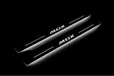 Two long door sill plates with MDX lettering and edges illuminated in white, angled view on a dark background.