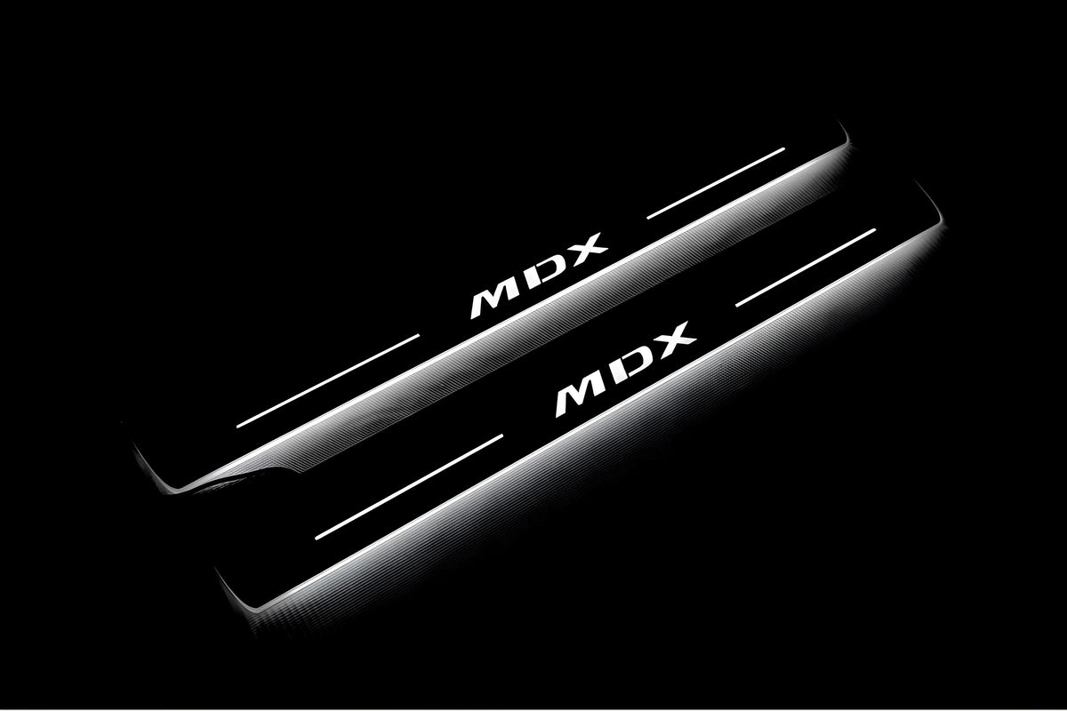 Two long door sill plates with MDX lettering and edges illuminated in white, angled view on a dark background.