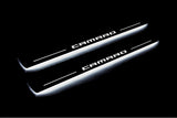 Two long door sill plates with Camaro lettering and edges illuminated in white, angled view on a dark background.