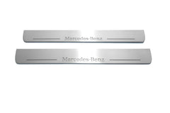 Two long silver-finished door sill plates with Mercedes-Benz lettering on a light background, straight-on view.