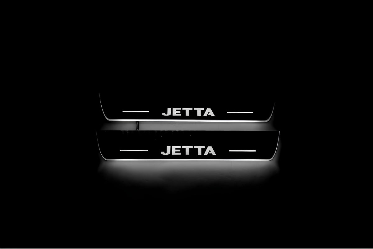 Two short door sill plates with Jetta lettering and edges illuminated in white, straight-on view on a dark background.