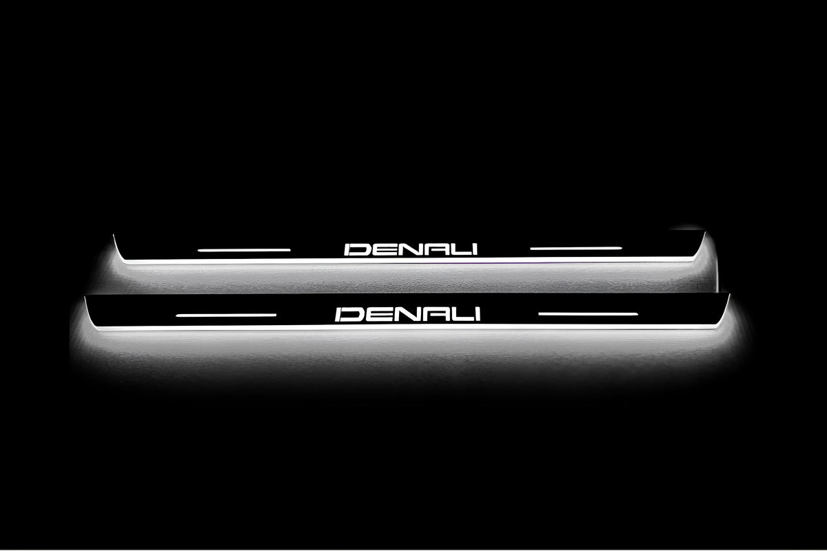 Two short door sill plates with Denali lettering and edges illuminated in white, straight-on view on a dark background.