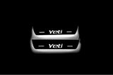 Two short door sill plates with Yeti lettering and edges illuminated in white, straight-on view on a dark background.