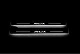 Two long door sill plates with MDX lettering and edges illuminated in white, straight-on view on a dark background.