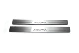 Two long silver-finished door sill plates with Acura lettering on a light background, straight-on view.