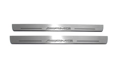 Two long silver-finished door sill plates with AMG lettering on a light background, straight-on view.