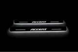 Two long door sill plates with Accent lettering and edges illuminated in white, straight-on view on a dark background.