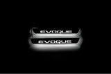 Two short door sill plates with Evoque lettering and edges illuminated in white, straight-on view on a dark background.