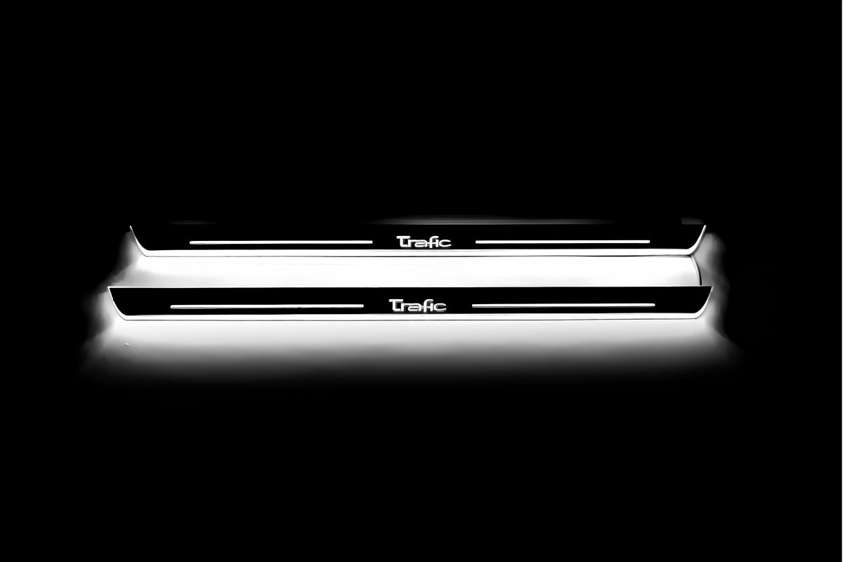 Two long door sill plates with Trafic lettering and edges illuminated in white, straight-on view on a dark background.