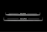 Two long door sill plates with Acura lettering and edges illuminated in white, straight-on view on a dark background.