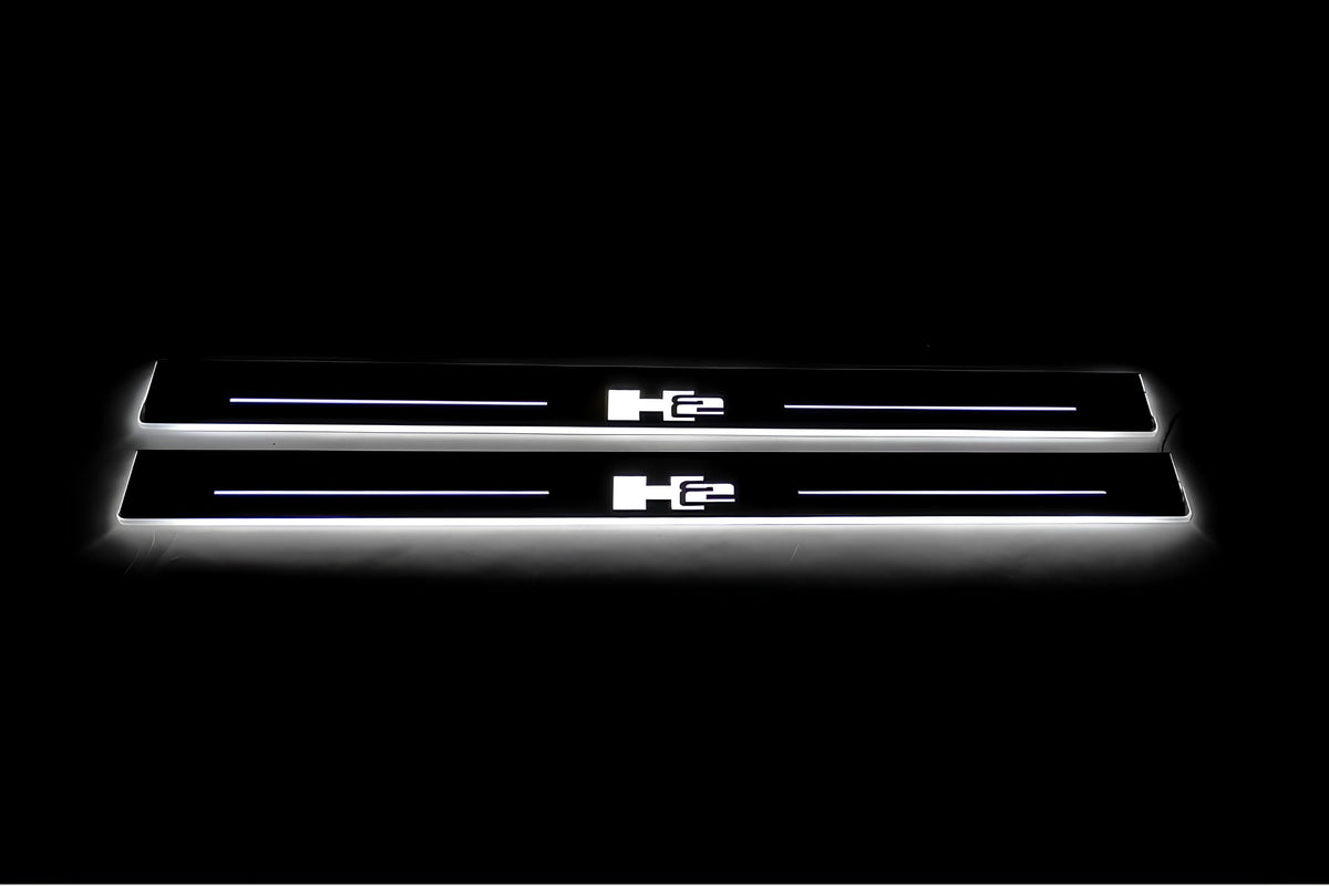 Two long door sill plates with H2 lettering and edges illuminated in white, straight-on view on a dark background.