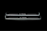 Two long door sill plates with X-Trail lettering and edges illuminated in white, straight-on view on a dark background.