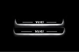 Two long door sill plates with Yeti lettering and edges illuminated in white, straight-on view on a dark background.